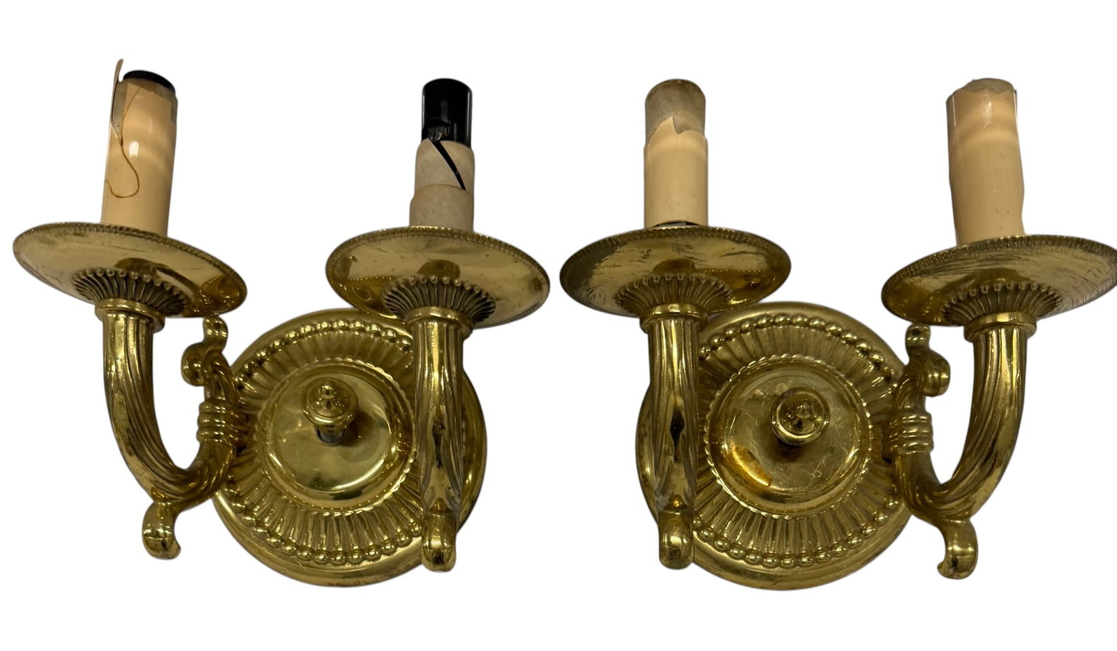 Pair of Louis XVI Style Gilt Bronze Two-Light Sconces: A distinguished pair of gilt bronze two-light sconces, crafted in the elegant Louis XVI style. Each sconce features an ornate circular backplate adorned with Neoclassical motifs, including fluting and