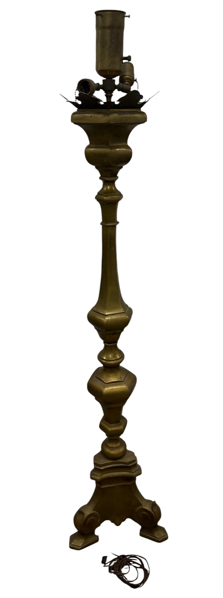 Patinated Brass Standard Lamp: A heavily patinated brass standard lamp. The lamp features a classical baluster form with a tripartite scrolling base. The stem is adorned with ornate turned elements, culminating in a three-light