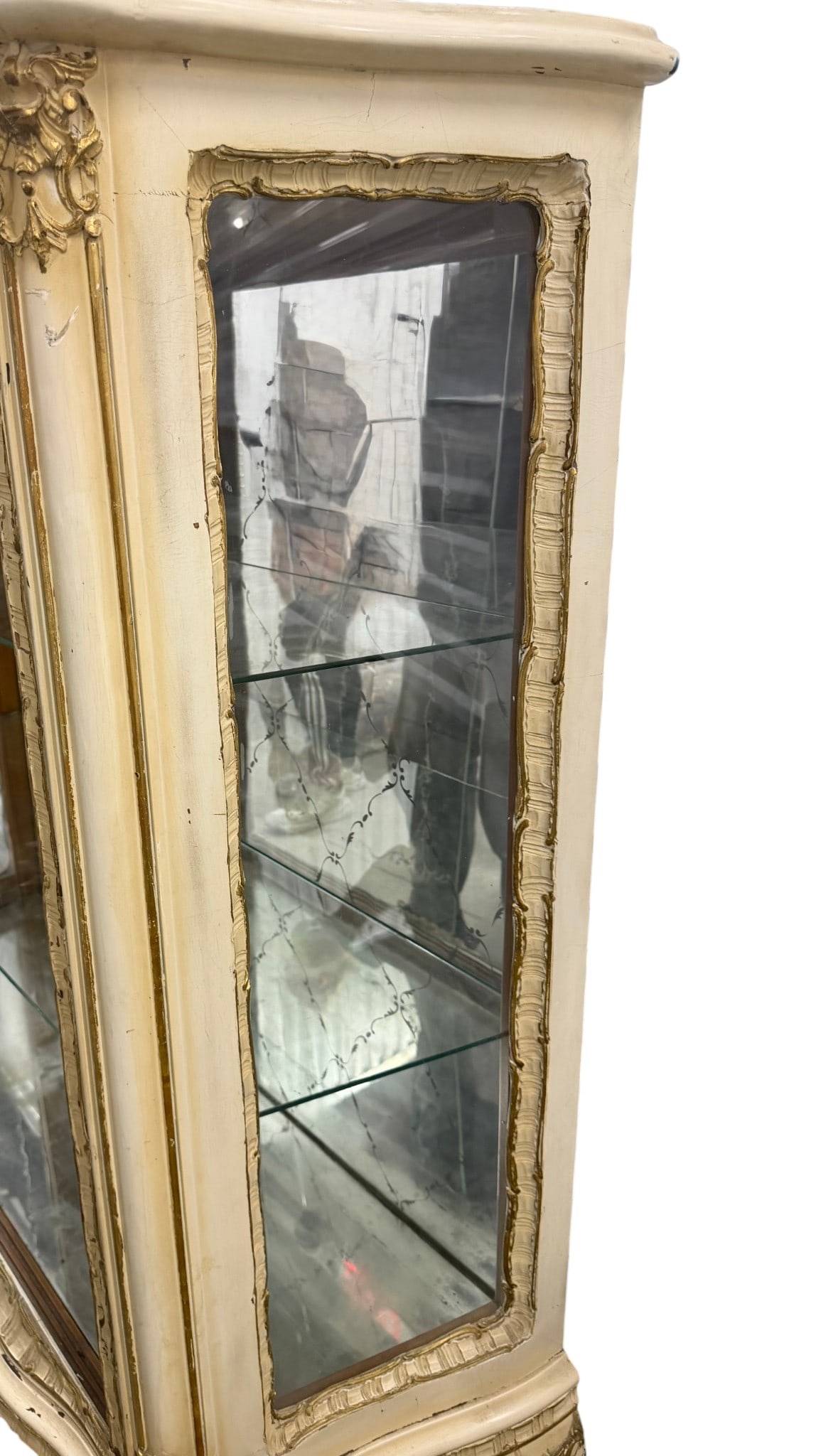 Italian Rococo Style Vitrine: An elegant Italian Rococo style vitrine, likely dating from the mid-20th century. This display cabinet features a distressed off-white painted finish with gold accents, highlighting the ornate carved
