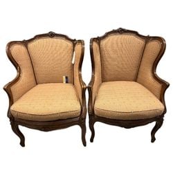 Pair of French Provincial Wingback Armchairs: A sophisticated pair of French Provincial style wingback armchairs, dating from the mid-20th century. These chairs feature elegantly carved dark wood frames with subtle floral motifs at the crest rail