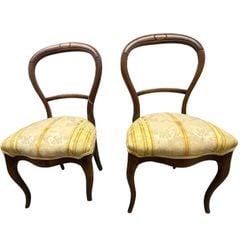 Pair of Rococo Revival Balloon Back Side Chairs: A pair of Rococo Revival side chairs, featuring elegant balloon backs crafted from dark stained wood with subtle carved detailing at the crest. The seats are upholstered in a jacquard fabric with a ye