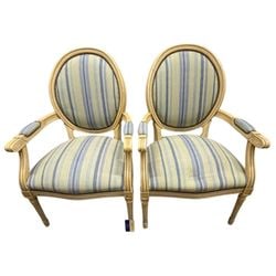 Pair of Louis XVI Style Painted Fauteuils: A pair of Louis XVI style fauteuils, featuring a painted and distressed finish on the frames, likely beechwood or similar hardwood. Each chair boasts an oval backrest and a generous, rounded seat,