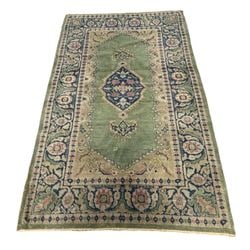 Antique Oushak Green and Blue Medallion Rug: An antique hand-knotted Oushak rug, likely late 19th or early 20th century, featuring a central medallion design in shades of green, rust, and blue. The rug displays traditional Oushak motifs with a f