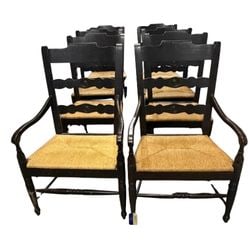 Set of Eight French Provincial Ladderback Armchairs: A set of eight French Provincial ladderback armchairs, late 19th or early 20th century, crafted from dark-stained wood with rush seats. Each chair features a shaped top rail over three wavy, carved
