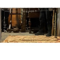 Venetian Style Etched Glass Mirror: A rectangular Venetian style mirror, likely mid-20th century, crafted with a beveled edge and etched with elegant foliate and floral motifs in the corners and center. The clear glass etching reveals