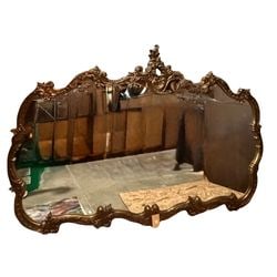 Large Giltwood Rococo Style Wall Mirror: An ornate and large giltwood mirror crafted in the Rococo style, likely dating from the mid-20th century. The frame features elaborate scrollwork, acanthus leaves, and shell motifs, characteristic of