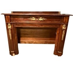 French Empire Style Mahogany and Gilt Bronze Fireplace Mantel: This elegant fireplace mantel is crafted in the French Empire style, likely dating to the early 20th century. Constructed from rich mahogany, it features classical gilt bronze mounts. The frieze is