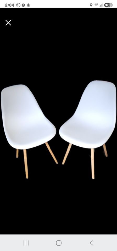 2 vintage mid-century modern style molded shell chairs originally designed by Charles & Ray Eames.: These iconic dining room or side chairs feature a molded plastic (polypropylene) shell seat with a curved, ergonomic backrest and tapered wooden legs. Scandinavian-inspired design. The chairs are lite