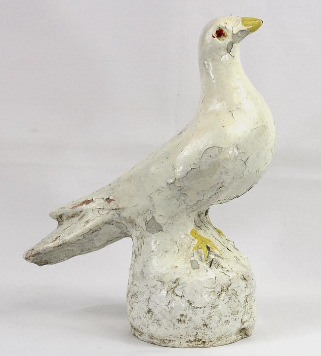An old concrete dove sculpture: This is a concrete dove. It stands 10" high by about 8" long by 4" wide. It has several layers of old, crazed and weathered paint, white with yellow beak and feet and red eyes. The condition is good,