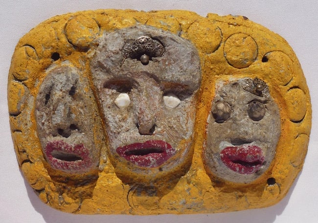 A concrete folk - outsider art plaque by Betty Davis: 3 women's faces: This is a plaque with three women's faces. Two of them are wearing costume jewelry. It is unusual and folky made from concrete and found objects then painted. It was done by Betty Davis, an outsider
