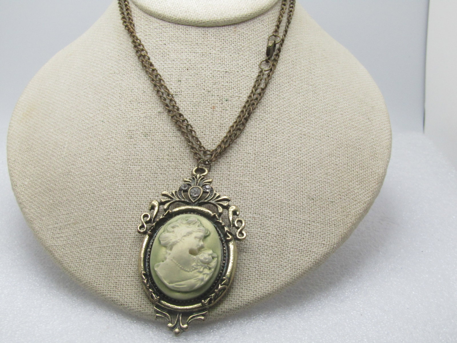 Vintage Green/White Cameo Necklace, 26", 1980's-1990's: Vintage Green/White Cameo Necklace, 26", 1980's-1990's. This is made to look like a Victorian style piece with the metal being treated to look antiqued. It has three clear rhienstones in the scrolled 