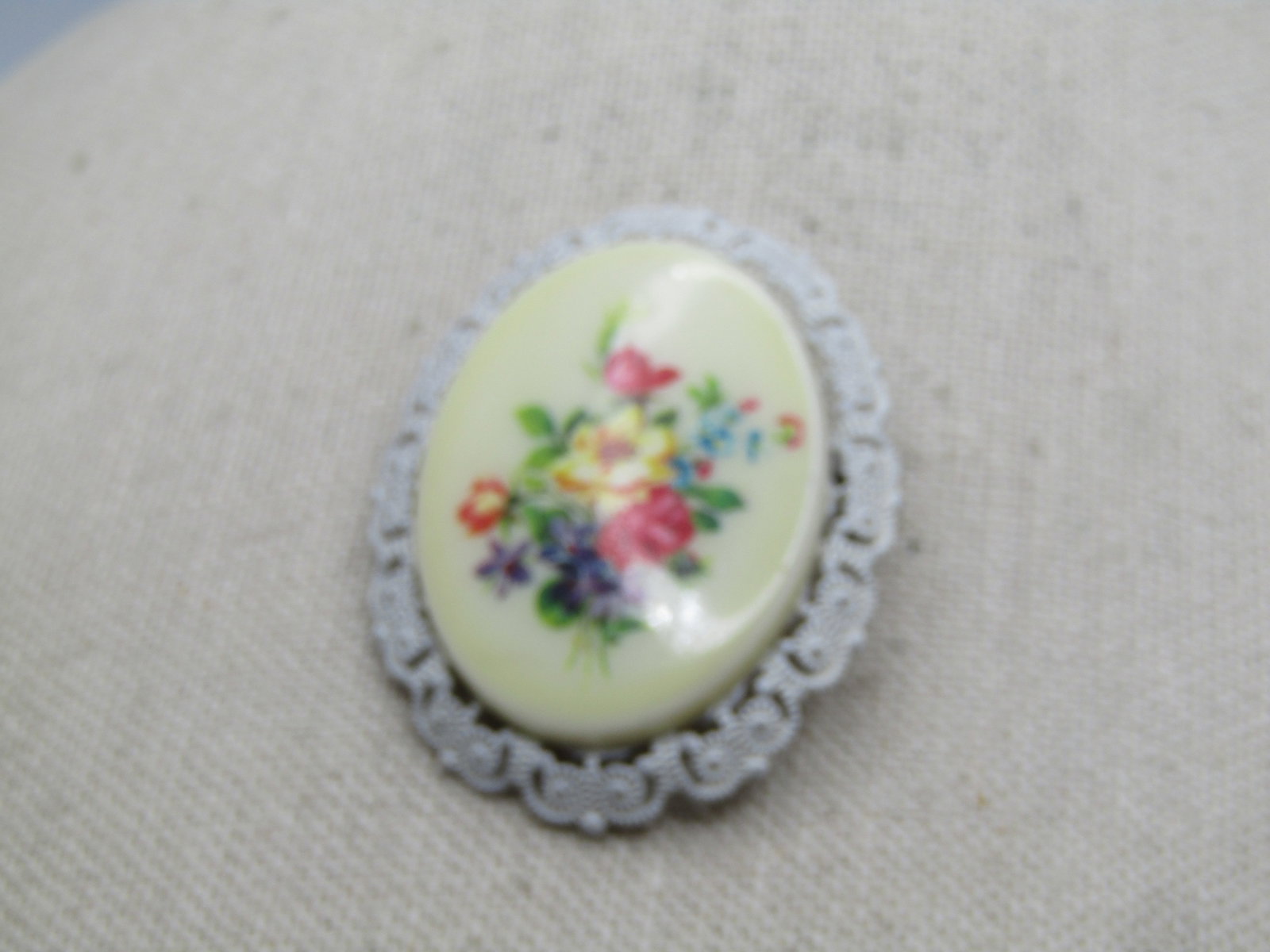 Vintage Floral Cameo Style Brooch, Germany, 1950's-1960's: Vintage Floral Cameo Style Brooch, Germany, 1950's-1960's. White enameled frame with a floral transfer design set on the oval off white plastic cameo-like center. It is appx. 2" tall and 1.5" wide.. G