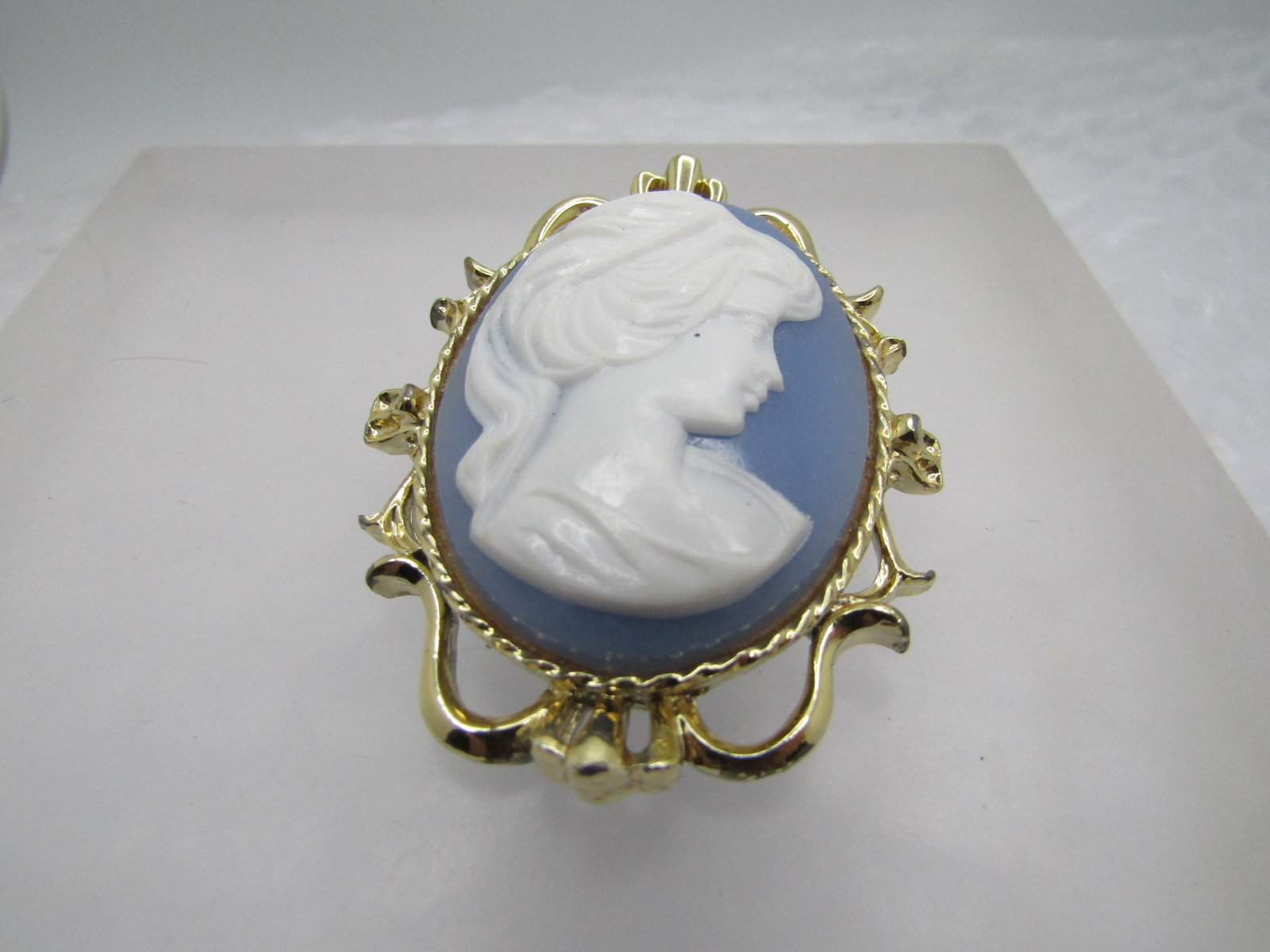 Vintage Blue & White Cameo Brooch, Signed Gerry's, 1960's: Vintage Blue & White Cameo Brooch, Signed Gerry's, 1960's. Gold tone oval scrolled frame. The blue and white molded cameo is made of plastic/acrylic. The brooch is appx.2.25" tall and 1.75". Very good