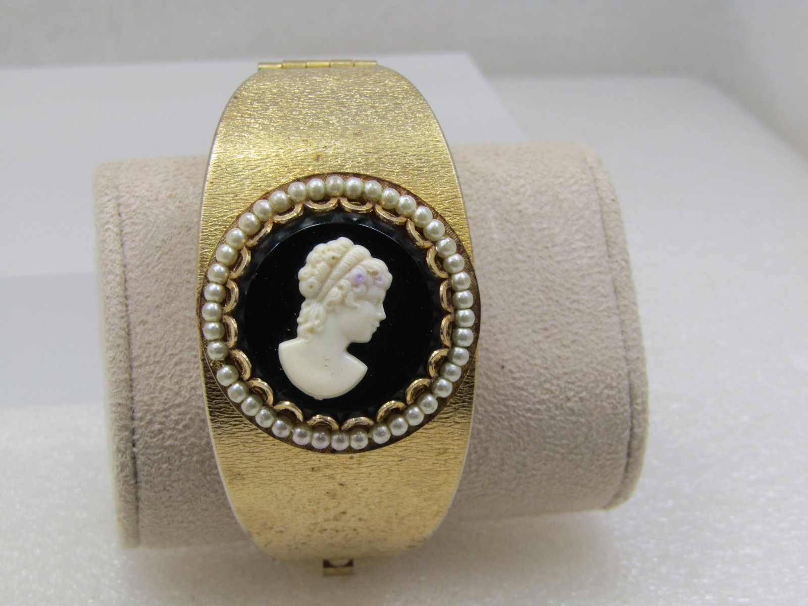 Vintage Wide Hinged Cameo Bracelet, 7", Gold tone, 1960's: Vintage Wide Hinged Cameo Bracelet, 7", Gold tone, 1960's. This is appx 1.25" wide at tp center and tapers as it moves around the right to appx. 5/8" at the back of the wrist. The hinge is on the side