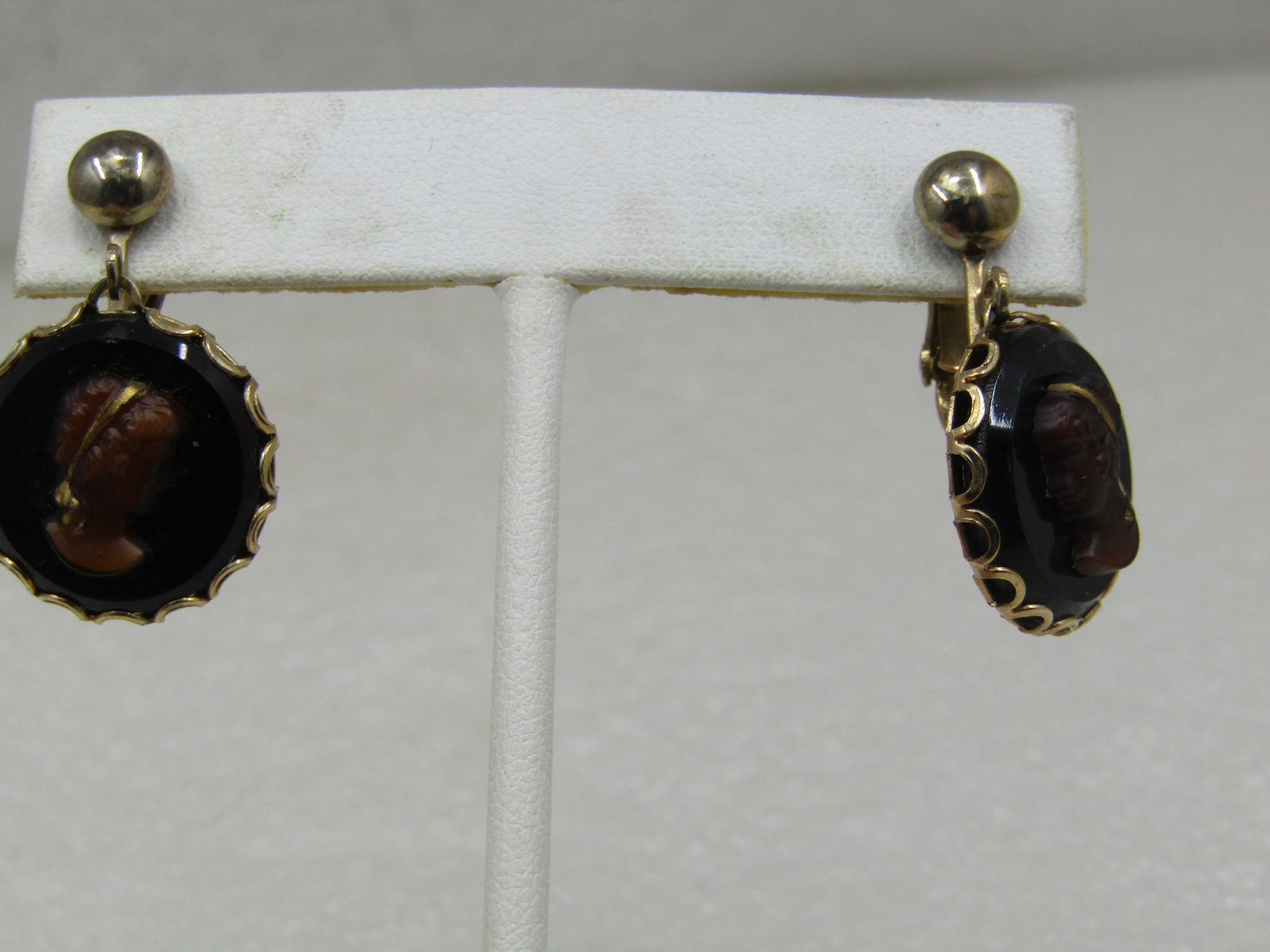 Vintage Cameo Drop Earrings, Clip, Signed Judy Lee: Vintage Cameo Drop Earrings, Clip, Signed Judy Lee in black and brown with scalloped bezel edge. Bead stud clip mechanism from which the cameos drop. Total length from stud is 1.25" and 3/4" wide. Gol