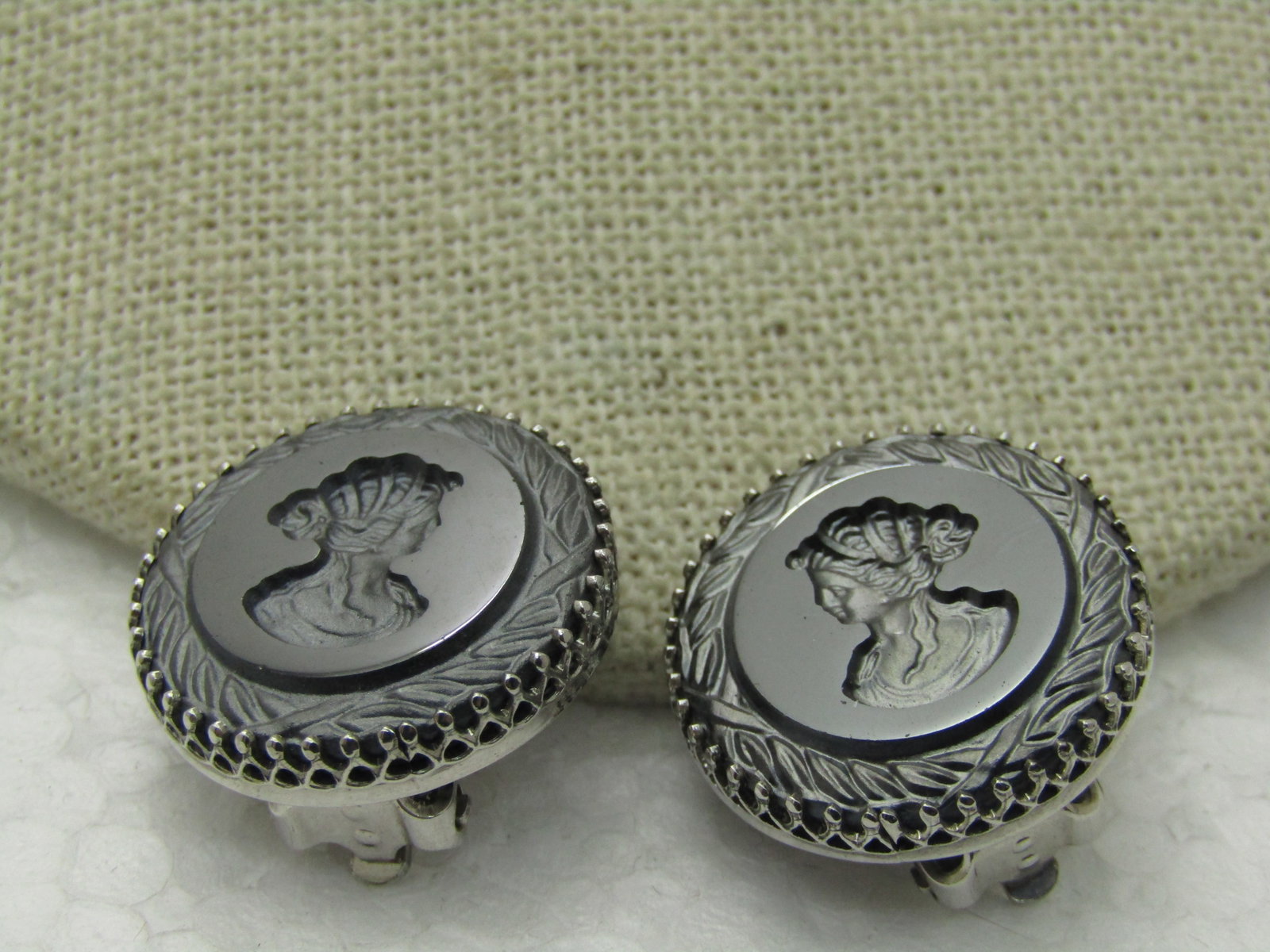 Vintage Whiting & Davis Intaglio Hematite Clip Earrings, 1960: Vintage Whiting & Davis Intaglio Hematite Clip Earrings, 1960, round with frosted finish on the cameo and decorative edge with a filigree bezel setting. 7/8" across. Signed Whiting & Davis. Very good