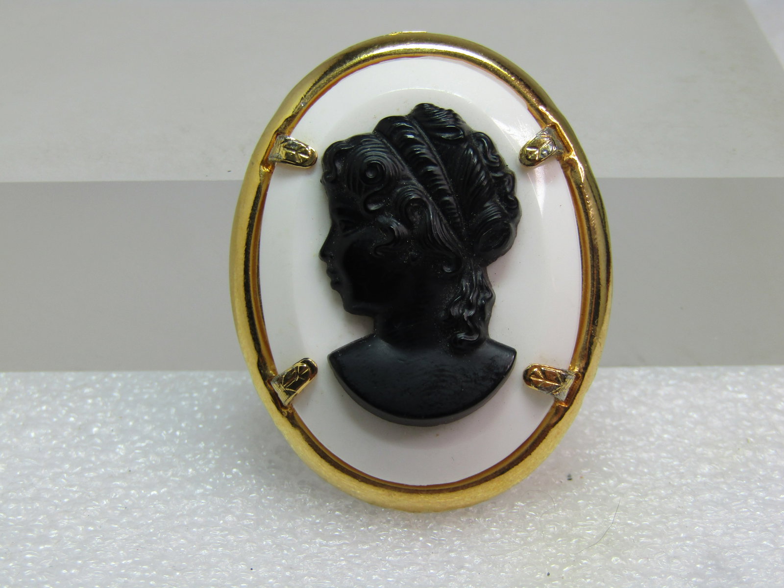 Vintage Black and White Cameo Brooch, 1960's-1970's, Lucite: Vintage Black and White Cameo Brooch, 1960's-1970's, Lucite. This is oval with a beveled whtie base and a molded black cameo on top. Gold tone oval frame with four heavy prongs. The brooch is appx. 1.