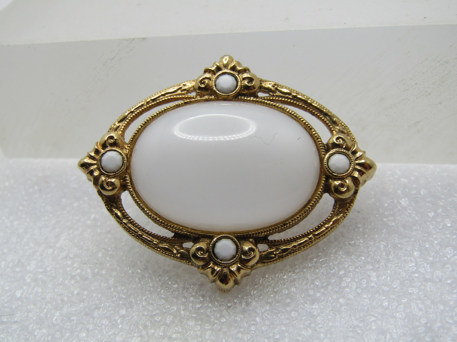 Vintage White Glass Beaded Brooch, Cameo-ish Style, 1960's-1970's: Vintage White Glass Beaded Brooch, Cameo-ish Style, 1960's-1970's. Oval gold tone with a stamped design and open work between the frame and the stone. It is appx. 1.5" by 1.25". Victorian themed .