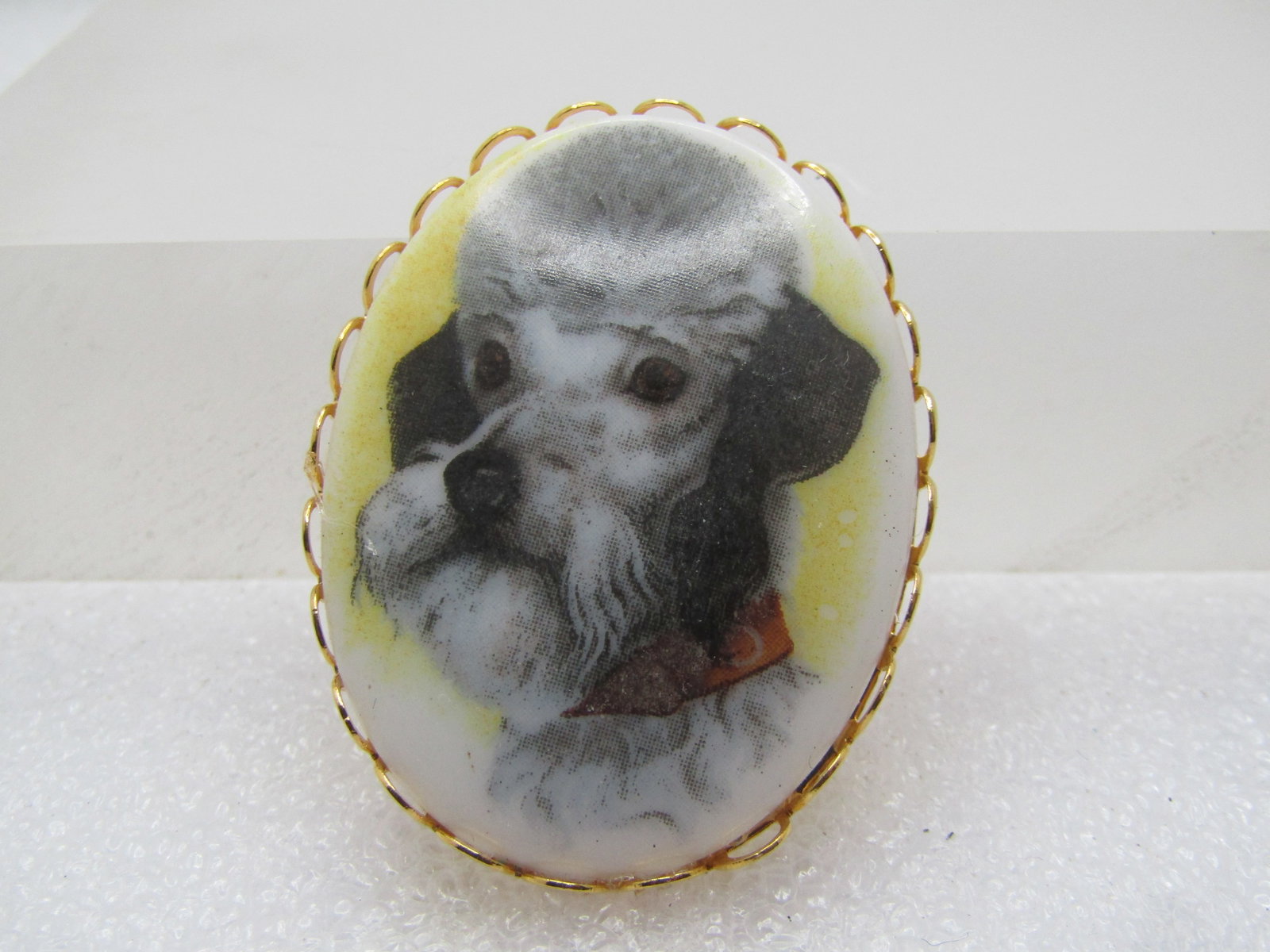 Vintage Poodle/Airdale Cameo Style Brooch, 1960's-1970's: Vintage Poodle /Airdale Cameo Style Brooch, 1960's-1970's. Gold tone with scalloped bezel frame. it is appx. 1.75" tall and 1.25" wide. Locking clasp. It has the loock of a poodle except for the