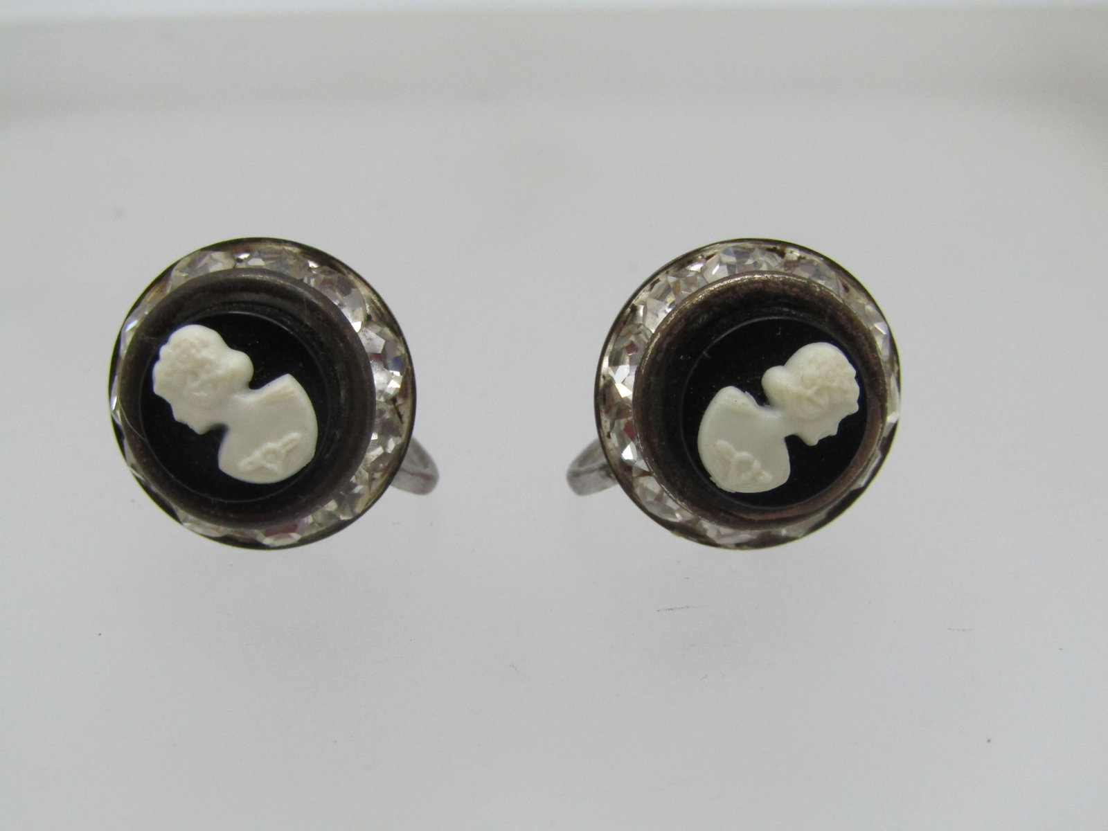 Vintage Rhinestone Cameo Earrings, Screwback, 1950's-1960's: Vintage Rhinestone Cameo Earrings, Screwback, 1950's-1960's. Black and white molded cameo with a frame of channel-set clear rhinestones. The earrings are appx. 5/8" across (slightly under but larger t