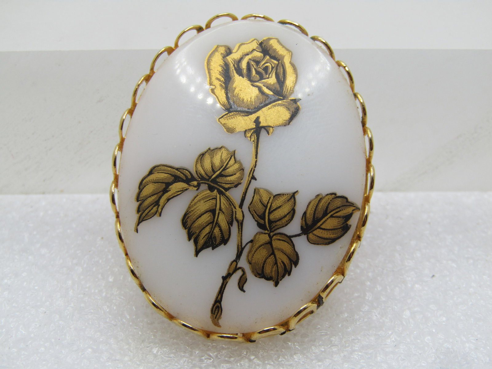 Vintage Gold Transfer Rose Brooch, Cameo Style, 1960's-1970's: Vintage Gold Transfer Rose Brooch, Cameo Style, 1960's-1970's. The brooch is oval white glass with a gold decal transer rose with black lined details set on the glass. Open scalloped bezel in gold