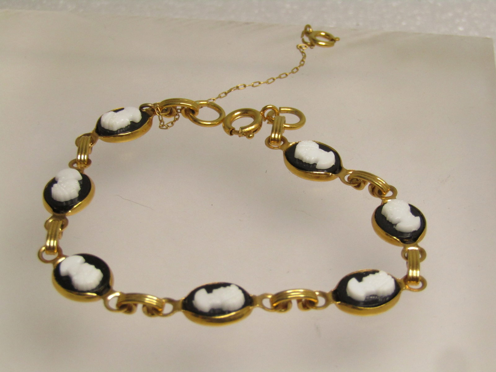 Vintage Black & White Cameo Bracelet, Safety Chain, 7.5" 1960's-1970's: Vintage Black & White Cameo Bracelet, Safety Chain, 1960's-1970's. 7.5", gold tone with spring ring clasp on the bracelet and the safety chain. Seven oval black and white molded cameo links with a