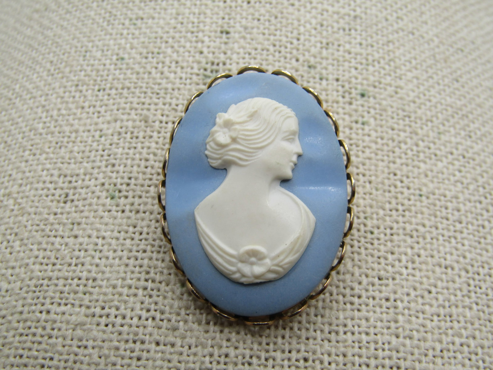 Vintage Faux Jasperware Cameo Brooch, 1960's: Vintage Faux Jasperware Cameo Brooch, 1960's. Gold tone oval that is appx. 1.25" tall and 1" wide. Scalloped gold tone bezel. Molded blue/white plastic to look like jasperware. Not signed by the