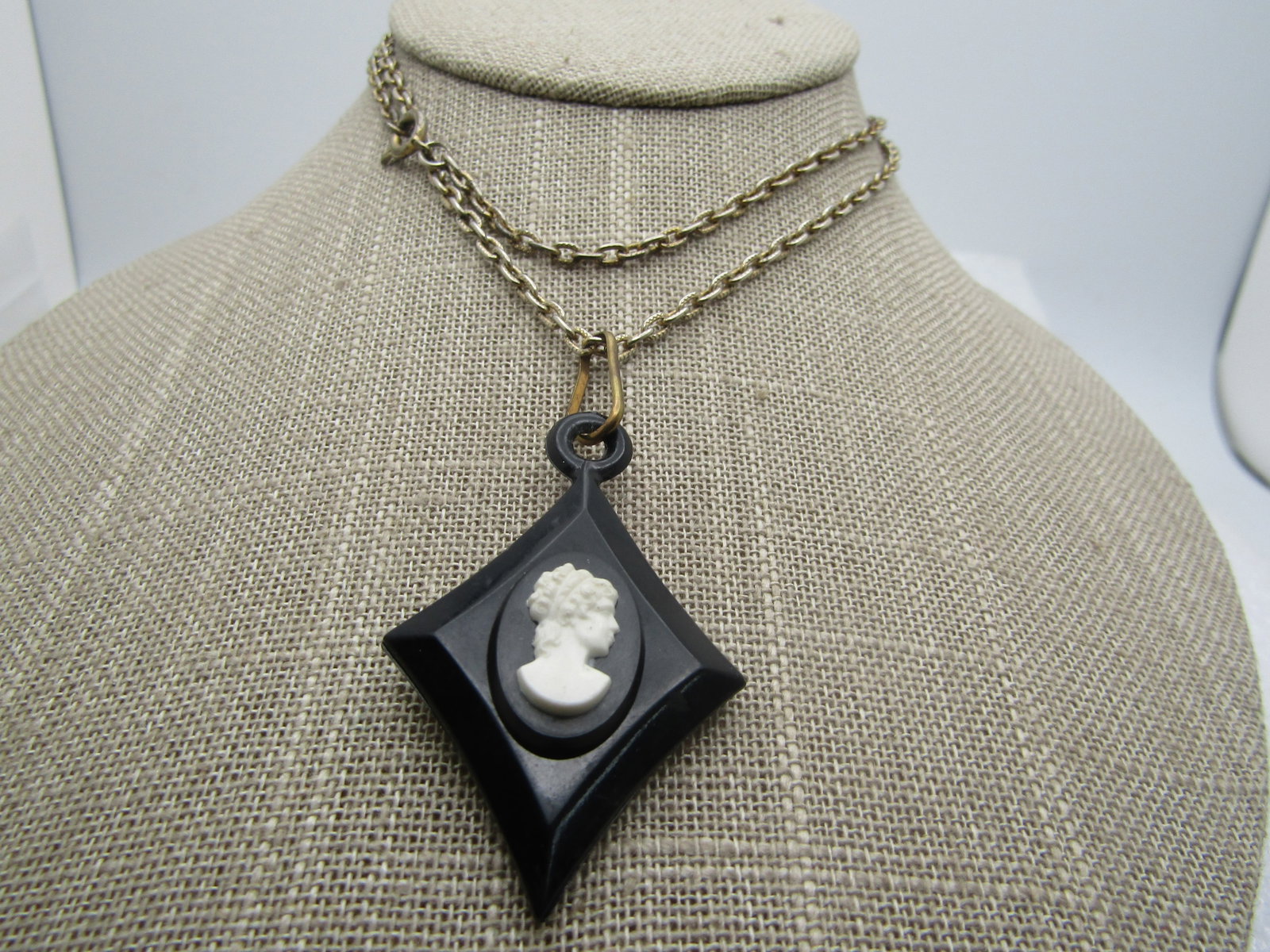 Vintage Black/White Cameo Necklace, Diamond Shape, 24", 1940''s: Vintage Black/White Cameo Necklace, Diamond Shape, 24", 1940''s. The pendant is appx. 2" by 1.25" wide. It is a molded acrylic/lucite with a rustic brass ring that attached is a 24" silver tone chain 