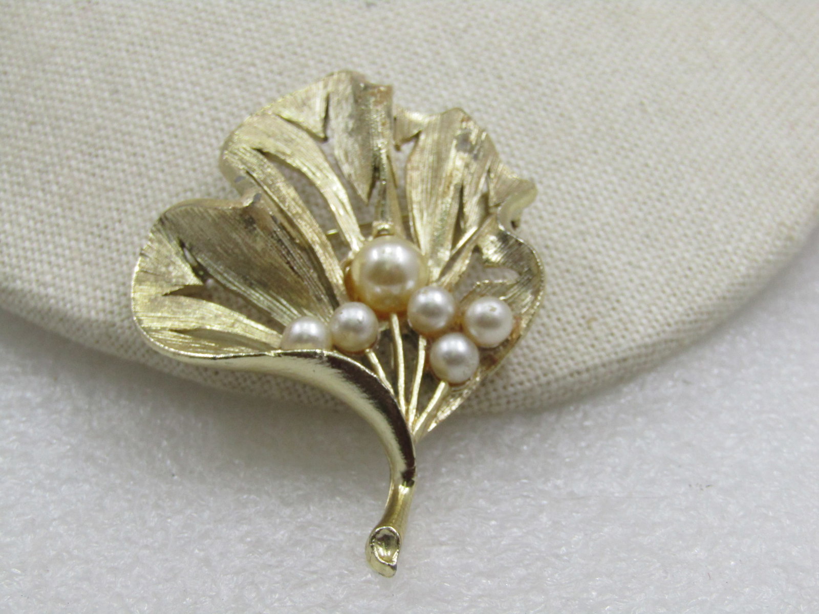 Vintage Gold Tone Faux Pearl Leaf Brooch, 1960's: Vintage Gold Tone Faux Pearl Leaf Brooch, 1960's. It is appx. 2.5" tall and 1.75" wide. It has 6 graduated pearls set in the base of the brooch. Textured finish with waves and curved in the design.