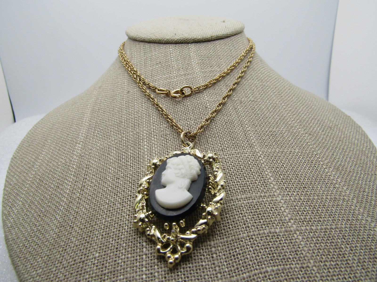 Vintage Black & White Cameo Necklace, 1960's, 26": Vintage Black & White Cameo Necklace, 1960's, 26". This has an open frame around the black adn white molded cameo. The pendant is appx. 2" long nad 1" wide. Gold tone with a 2mm rope chain and spring