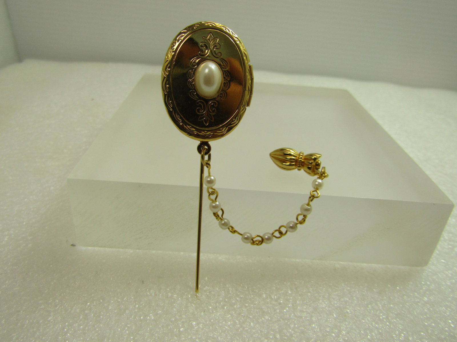 Vintage Faux Pearl Locket Stick Pin with Safety Clasp & Chain, 1960's-1970's: Vintage Faux Pearl Locket Stick Pin with Safety Clasp & Chain, 1960's-1970's. This is gold tone and appx. 3" tall with an ornate end cap and a chain connecting to the base of the locket that connects