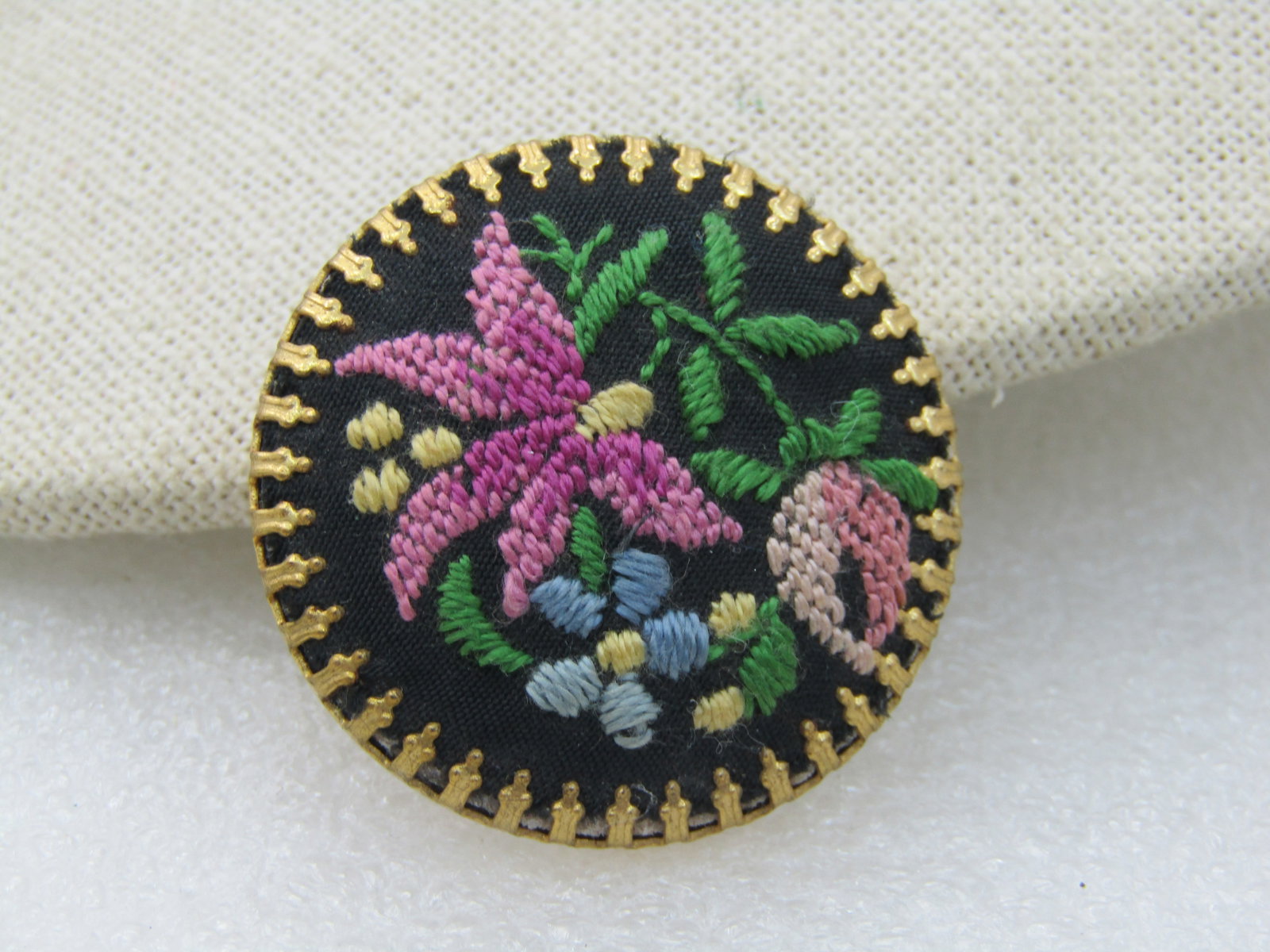 Vintage Black Floral Needlepoint Cameo Brooch , 1.5" Round: Vintage Black Floral Needlepoint Cameo Brooch , 1.5" Round. Pink flowers that could be a lily, rose, and forget-me-not with green leaves on a black background with crown-oint bezel-setting. 1960s.,