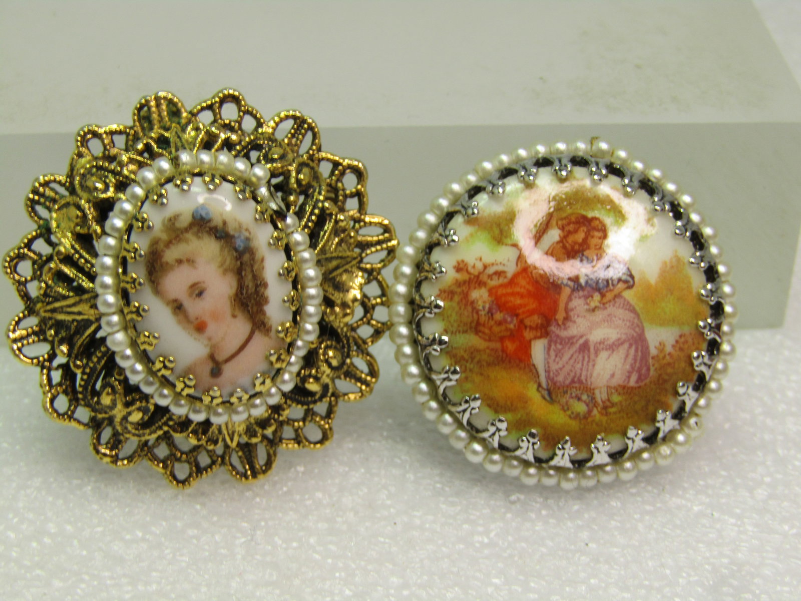 Vintage Pair Brooches, Cameo Style, Portrait/ Courting Scene, 1960's: Vintage Pair Brooches, Cameo Style, Portrait/ Courting Scene, 1960's. The first - the portrait brooch is also a pendant. It has a filigree double frame in gold tone with a halo of faux pearls around t