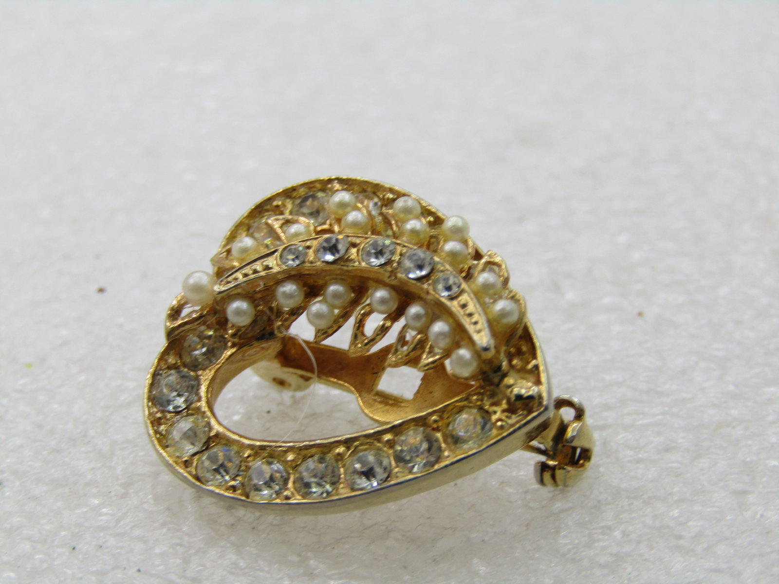 Vintage Rhinestone & Faux Pearl Heart Brooch, 1960's-1970's: Vintage Rhinestone & Faux Pearl Heart Brooch, 1960's-1970's, 1" tall and 7/8" wide, gold tone. Clear rhinestones on the left side of the brocoh as you look a it and also down the center of the faux pe