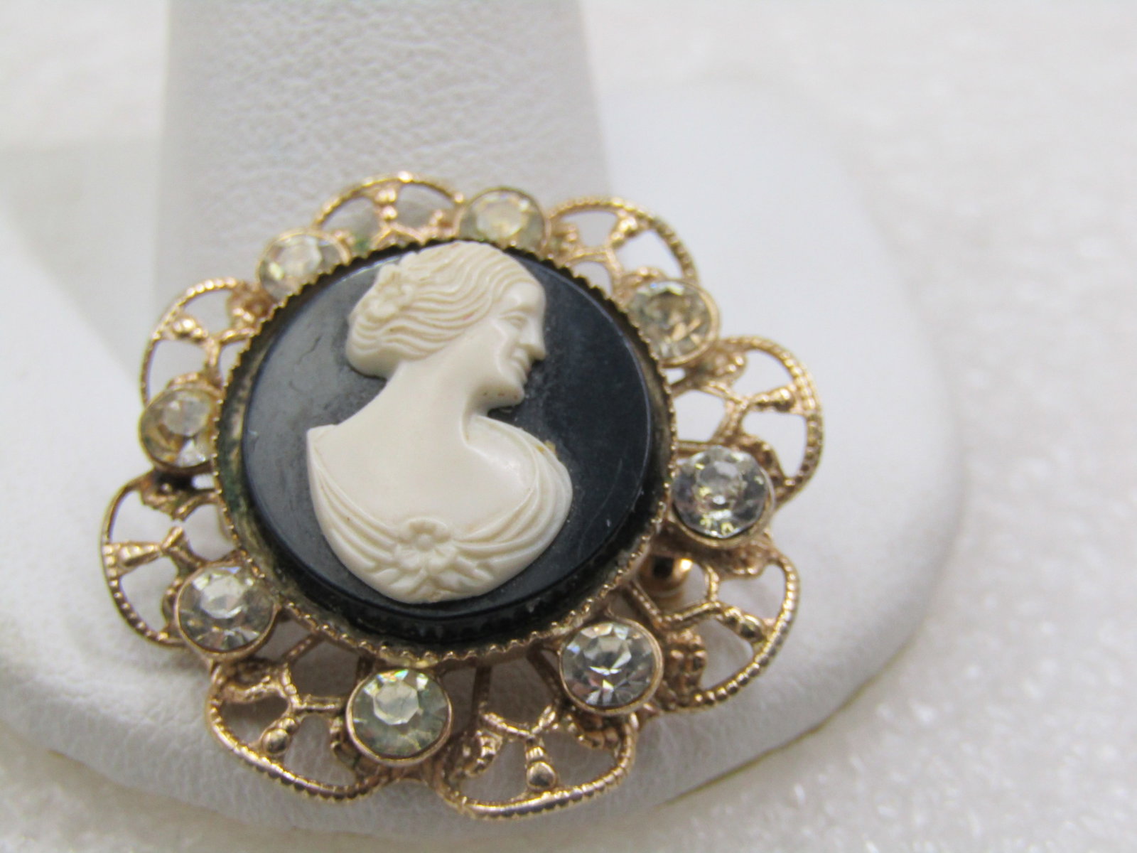 Vintage Black White Cameo Filgiree Brooch wiith Rhinestones, 1950's-1960's: Vintage Black White Cameo Filgiree Brooch wiith Rhinestones, 1950's-1960's. This is appx 1.25" across. The cameo is round and set in a bezel raised over the filigree base that is wavy with clear rhine