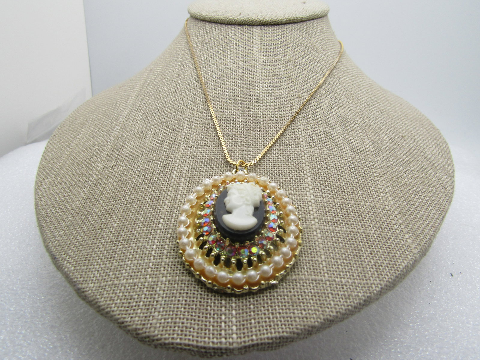 Vintage Cameo Rhinestone Pearl Necklace, Costume, 15", 1960's: Vintage Cameo Rhinestone Pearl Necklace, Costume, 15", 1960's. Gold tone. It is a black and white molded plastic cameo on top and cneter with a wider base that angles up toward the cameo with a halo o