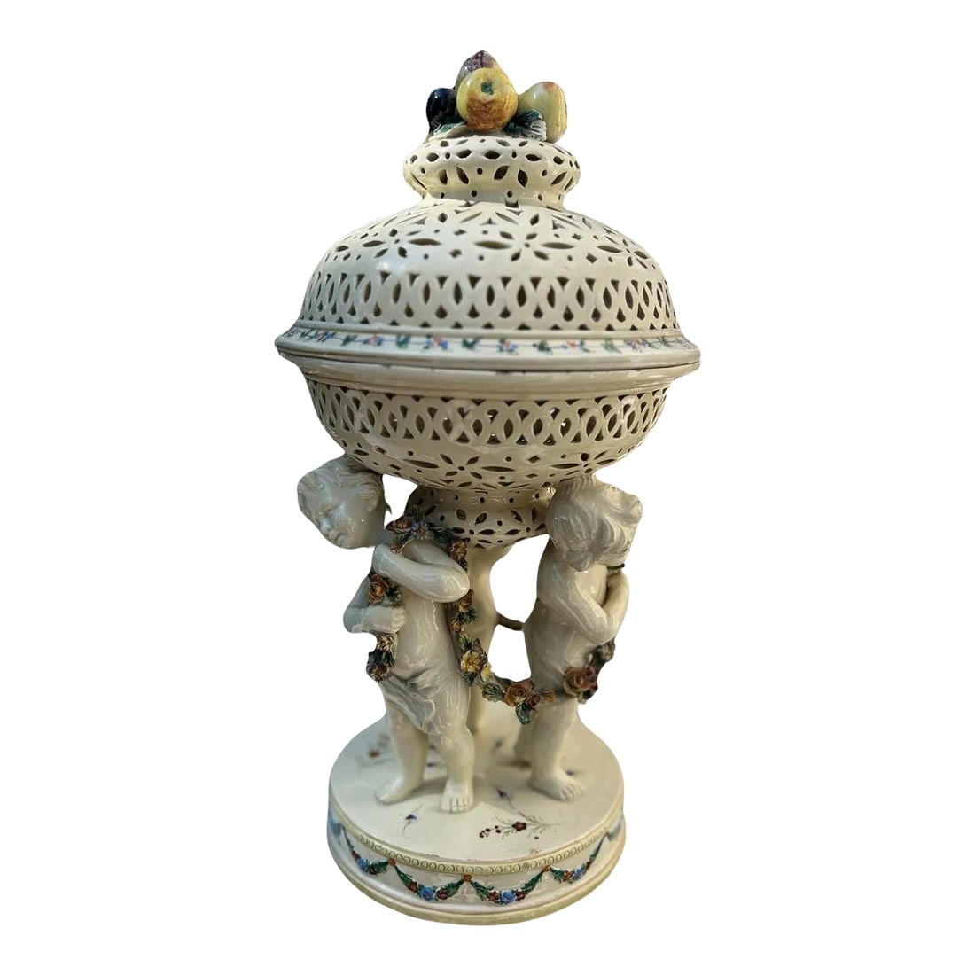 19th Century French Tin Glazed Creamware Centerpiece Adorned With Putti Supports: French, 19th century. A fine quality creamware centerpiece in two parts having a polychrome decorated swaged garland to base, 3 figural cherub which not only support a wonderful pierced top but also
