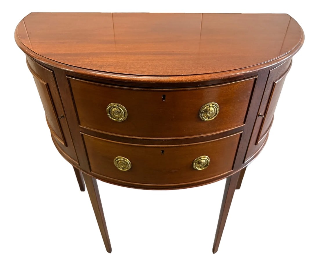 Late 20th Century Baker Furniture Historic Charleston Mahogany Demilune Cabinet or Sideboard: Baker Furniture Historic Charleston Mahogany Demilune Cabinet or Sideboard This beautiful piece has 4 tapered legs that support the demilune shape. There are two central drawers with round brass