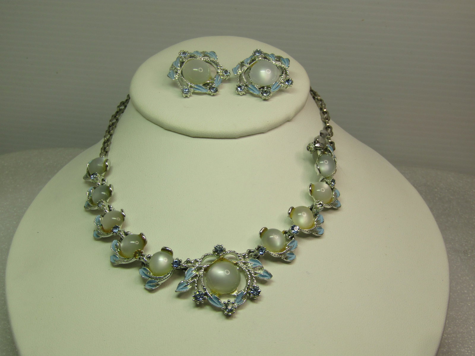 Vintage Faux Moonstone Blue RS Necklace, Bracelet, Clip Earrings, 1960's: Vintage Faux Moonstone Blue RS Necklace, Bracelet, Clip Earrings, 1960's. Silver tone set with white faux moonstone and curved blue enameled leaves with baby blue rhinestones accenting the pieces. The