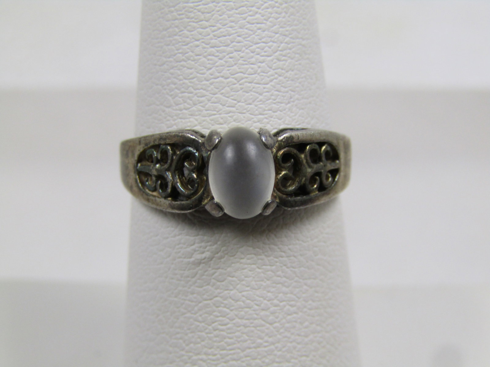 Vintage Sterling White Cateye Ring, Scrolled, Sz. 7, 1960's-1970's: Vintage Sterling White Cateye Ring, Scrolled, Sz. 7, 1960's-1970's. The ring has a white oval cateye stone on top - likely glass. The stone is appx. 6.5mm by 4.5mm. It has an open work scroll one each