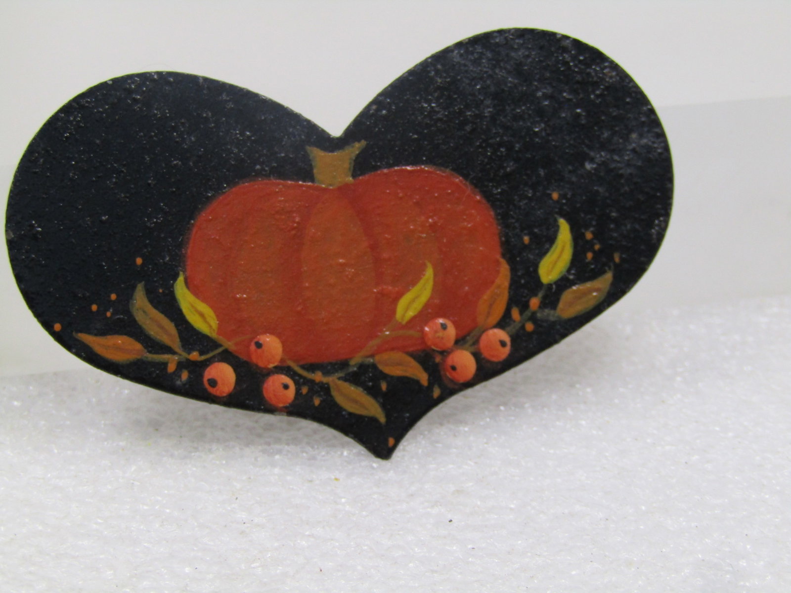 Vintage Tole Painted Pumpkin Heart Brooch, 1970's: Vintage Tole Painted Pumpkin Heart Brooch, 1970's. This is a metal elongated heart that is painted black on front and weathered on the back with a pumpkin and leaves and berries on the front. It is ap