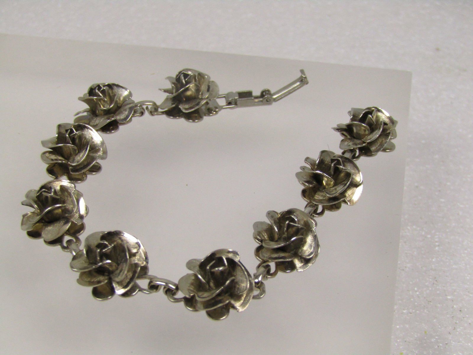 Vintage Rose Blossom Bracelet, Silver Tone, 7", 1960's-1970's: Vintage Rose Blossom Bracelet, Silver Tone, 7", 1960's-1970's. It has a flip clasp and the roses make up nine-links and are appx 1/2" wide. The back of the rose has a flat surface and each link is con