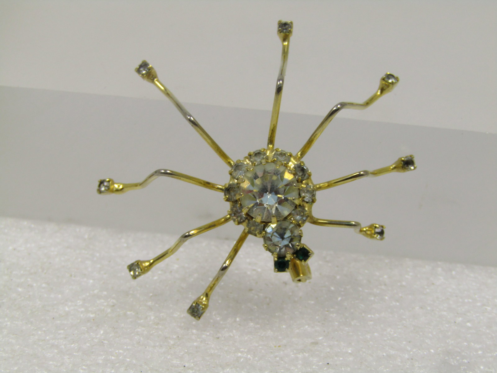 Vintage Rhinestone Spider Brooch, 1960's-1970's: Vintage Rhinestone Spider Brooch, 1960's-1970's. This has a gold tone spider with clear head, torso and halo of clear stones around the center round stone with prong-setting. Green rhinestone eyes. It