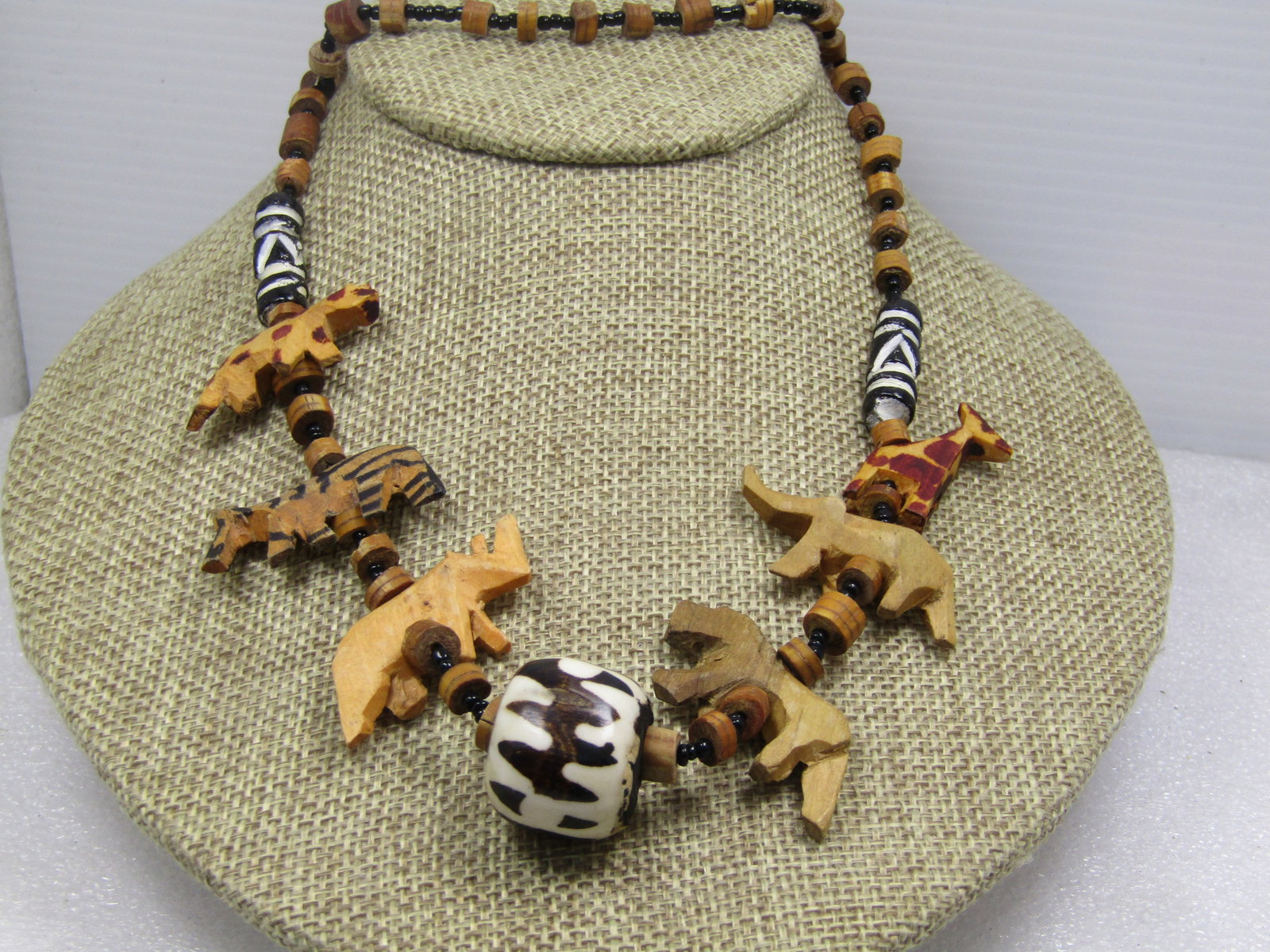 Vintage Carved African Animal Necklace, Black Seed Beads, 24". 1960's-1970's: Vintage Carved African Animal Necklace, Black Seed Beads, 24". 1960's-1970's. There is a larged black/white/brown drum-like tribla bead at center that is made of an unknown material. The animals are w