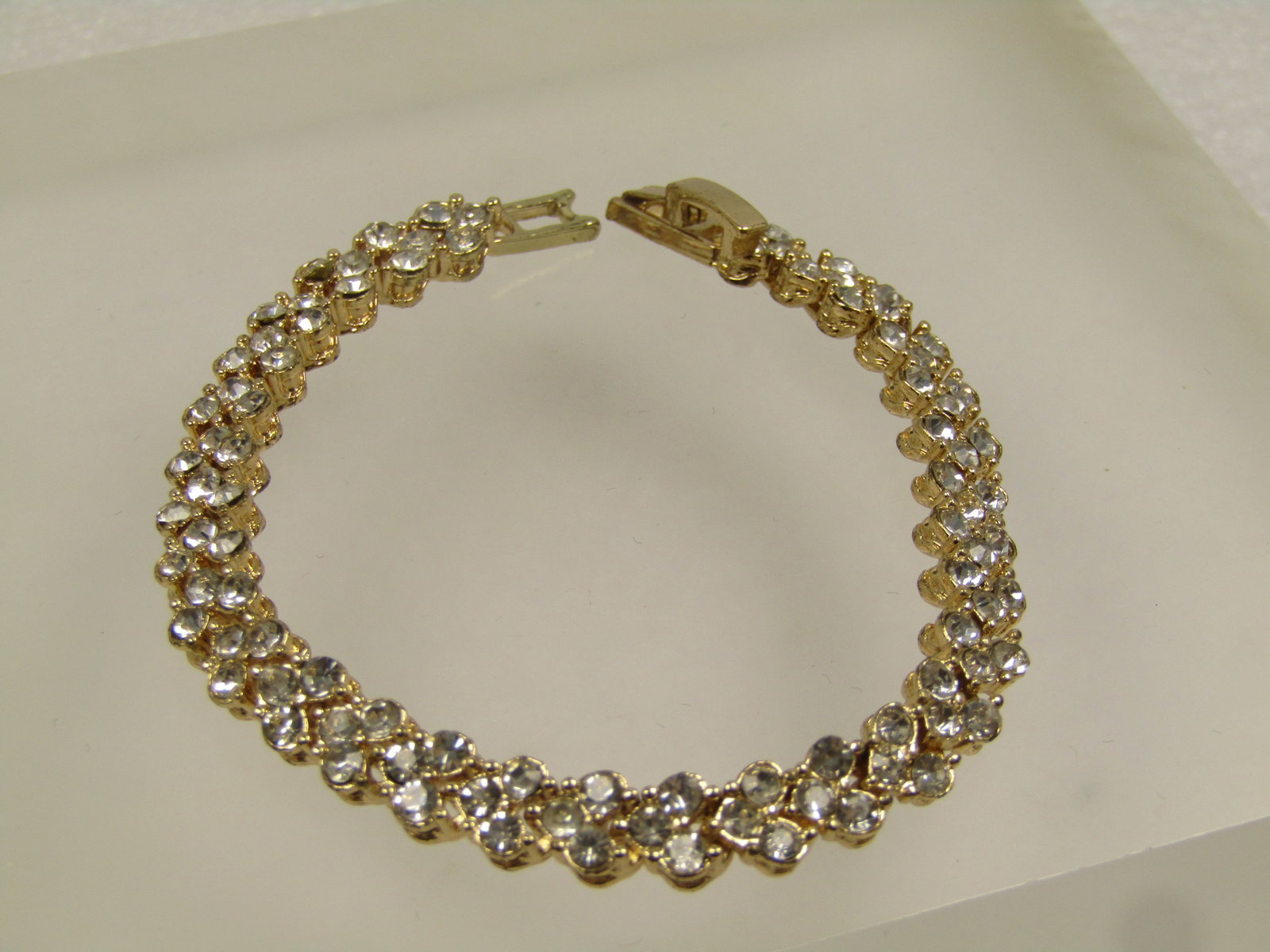 Gold Tone Rhinestone V Link Tennis Bracelet, 6.75", 1990's: Gold Tone Rhinestone Heart Link Tennis Bracelet, 6.75", 1990's. This si appx. 6.5mm. Each link has three clear stones and is in the shape of a heart. Very clean and in very good conditon. Flip clasp. 