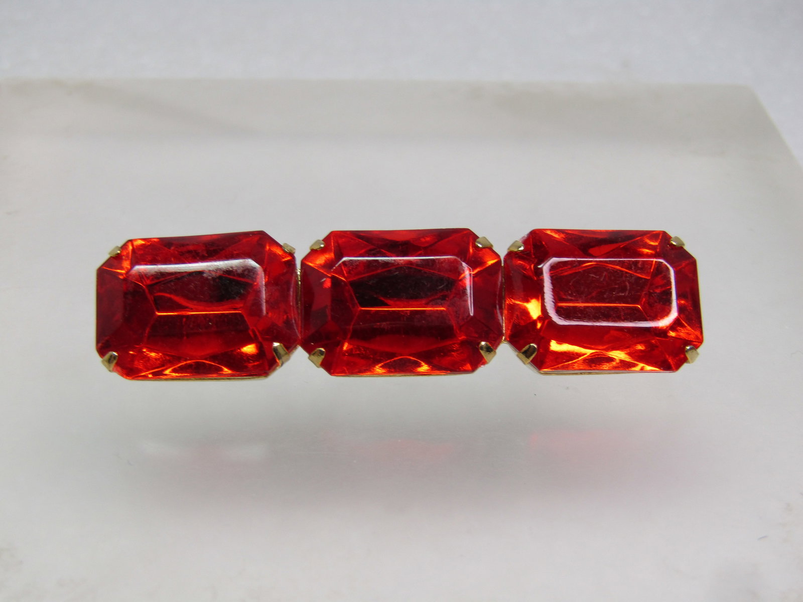 Vintage Orange/Red Rhinestone Bar Brooch, 1960's-1970's: Vintage Orange/Red Rhinestone Bar Brooch, 1960's-1970's. Large rectangular prong-set red/orange acrylic stones. The brooch has three stones that are each appx. 17.5mm by 13mm. Gold tone and set in a