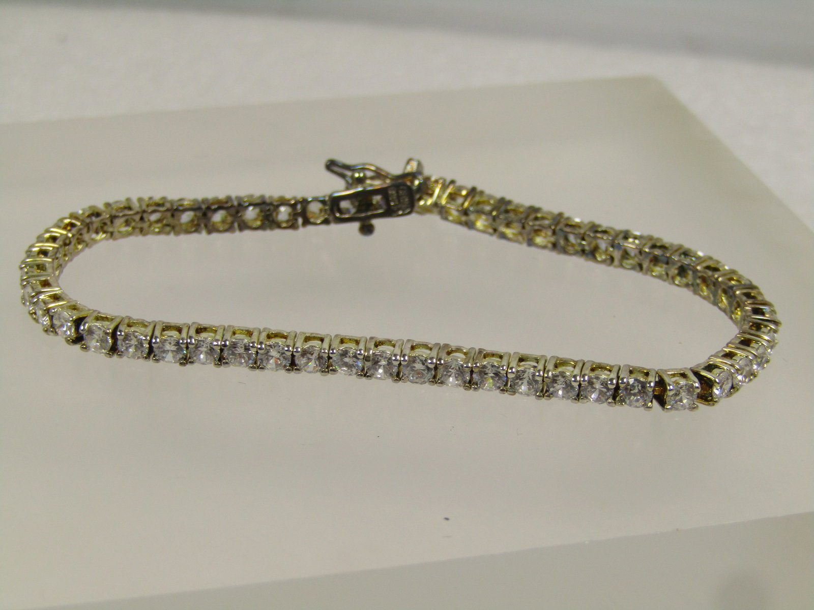 Clear CZ 3mm Wide Tennis Bracelet, Box Clasp with Safety Clips, 7", 1980's-1990's: Clear CZ 3mm Wide Tennis Bracelet, Box Clasp with Safety Clips, 7", 1980's-1990's. Gold tone . This is signed W1with an R and marked China. It is marked .925 but it is not sterling. It is a gold tone 