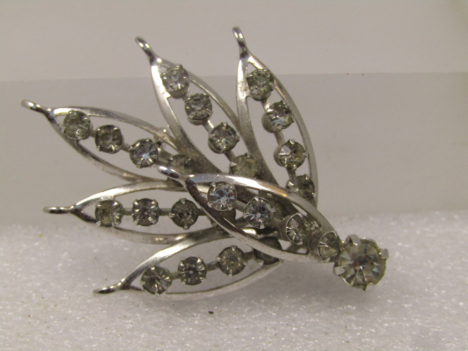 Vintage Clear Rhinestone Stem Brooch, 1960's: Vintage Clear Rhinestone Stem Brooch, 1960's, Silver tone stem brooch with raised clear rhinestones through the center of the open pointed elaves with a larger, 6mm round stone at the base. The brooch
