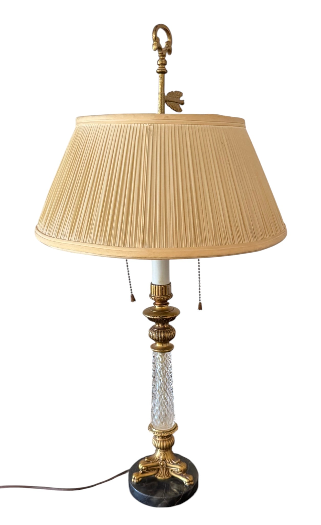 Gilt Bronze and Cut Glass Table Lamp: A sophisticated table lamp featuring a pleated cream fabric shade. The body is composed of a faceted cut glass column set within ornate gilt bronze mounts, resting on a black marble plinth. The lamp i