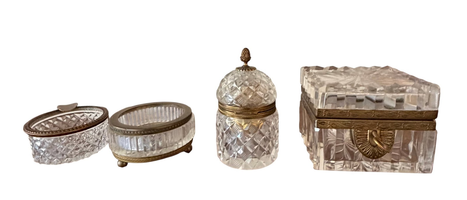 Collection of Four Antique Cut Glass and Gilt Metal Dresser Boxes, likely 19th Century: This exquisite collection features four antique dresser boxes, each crafted from meticulously cut glass and adorned with ornate gilt metal fittings. The lot includes an oval hinged box, an oval open s